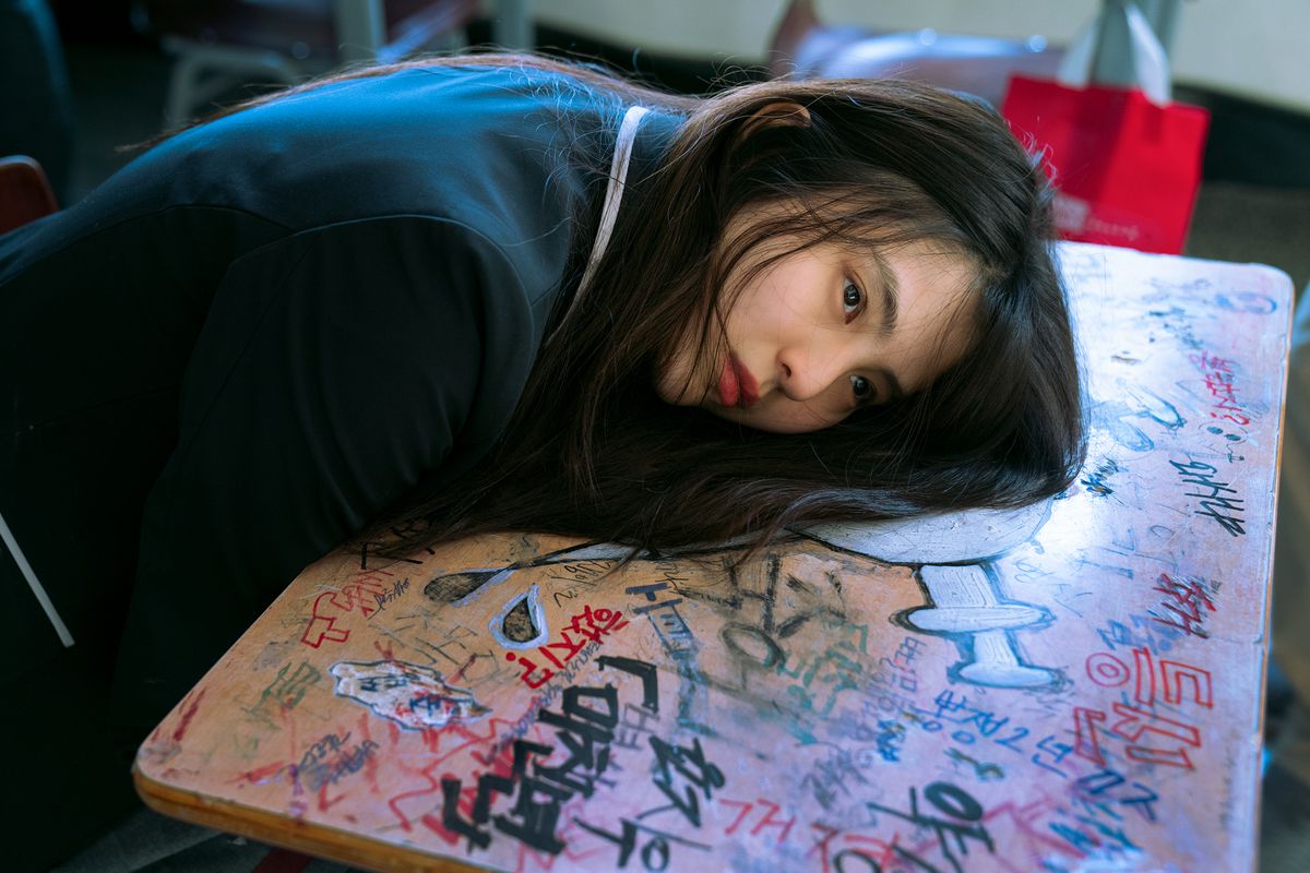 Han So-Hee appoggia la testa contro una scrivania con molti disegni su My Name.