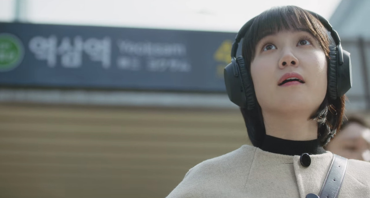 Eun Park-bin nei panni di Woo Young-woo che guarda il cielo con l'insegna della stazione della metropolitana dietro di lei