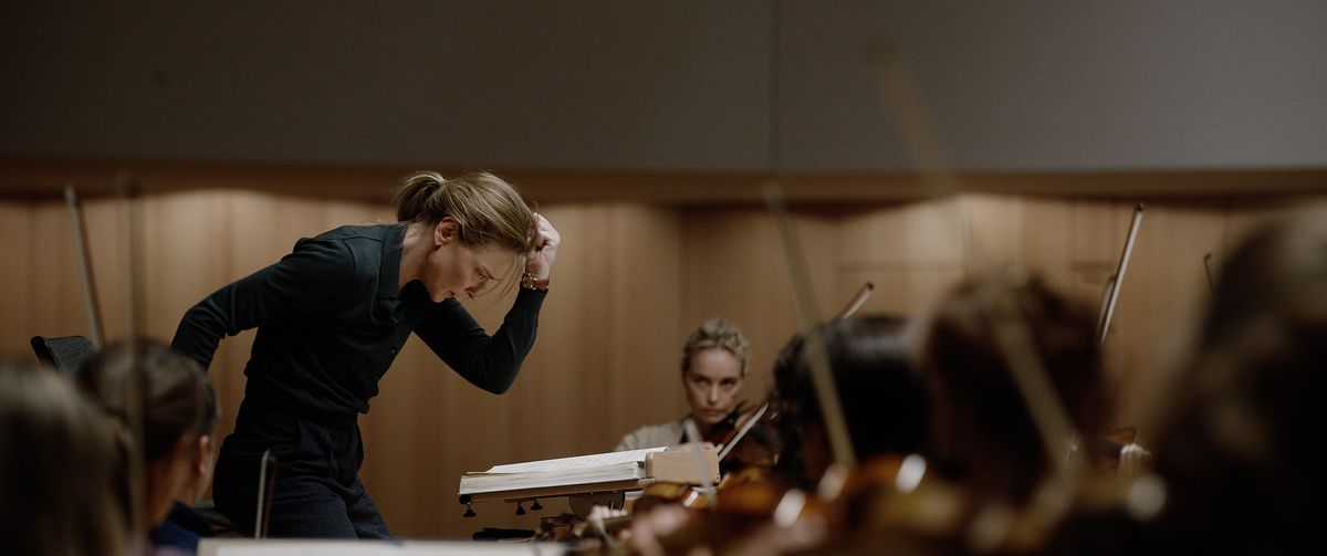 Lydia Tár (Cate Blanchett) fa un vigoroso gesto di tutto il corpo verso il basso mentre dirige la Filarmonica di Berlino nel Tár di Todd Field