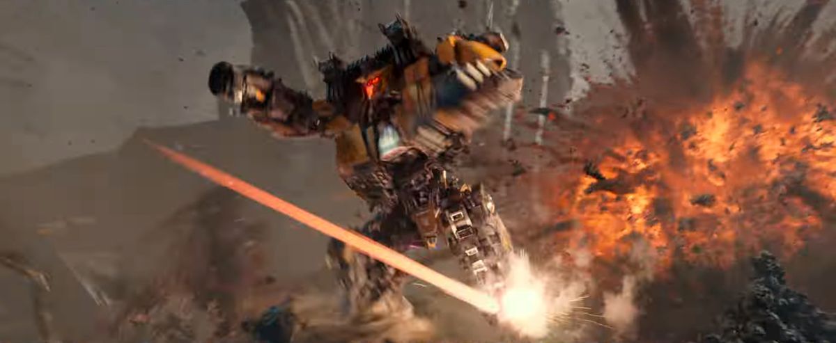 Un trasformatore giallo con una pistola in mano salta via da un'esplosione in Transformers: Rise of the Beasts
