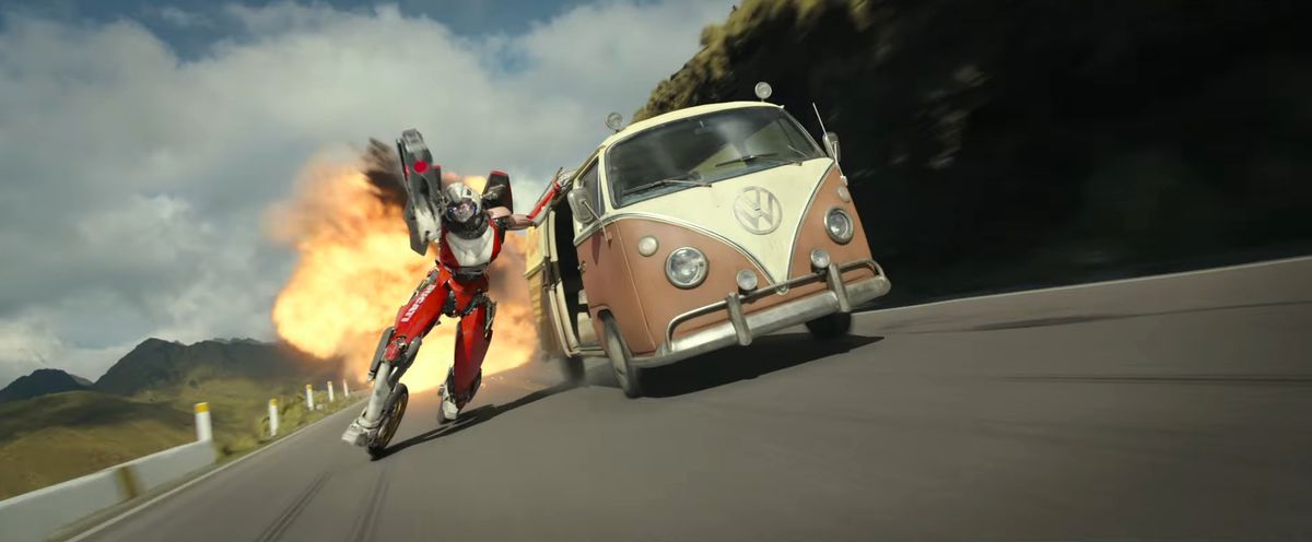 Acree il trasformatore usa i suoi piedi da motocicletta per guidare un insetto VW marrone lontano da un'esplosione durante un inseguimento in macchina in Transformers: Rise of the Beasts