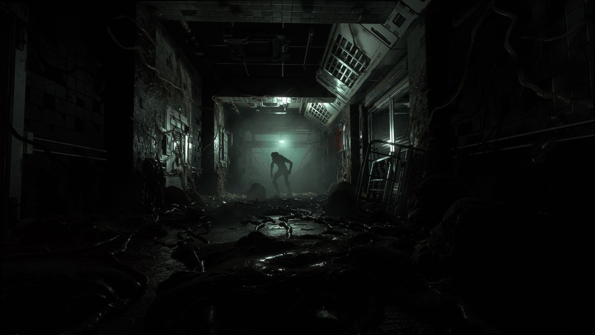 Un oscuro corridoio industriale è ricoperto di sangue e tentacoli, con un mutante sullo sfondo, in uno screenshot di The Callisto Protocol