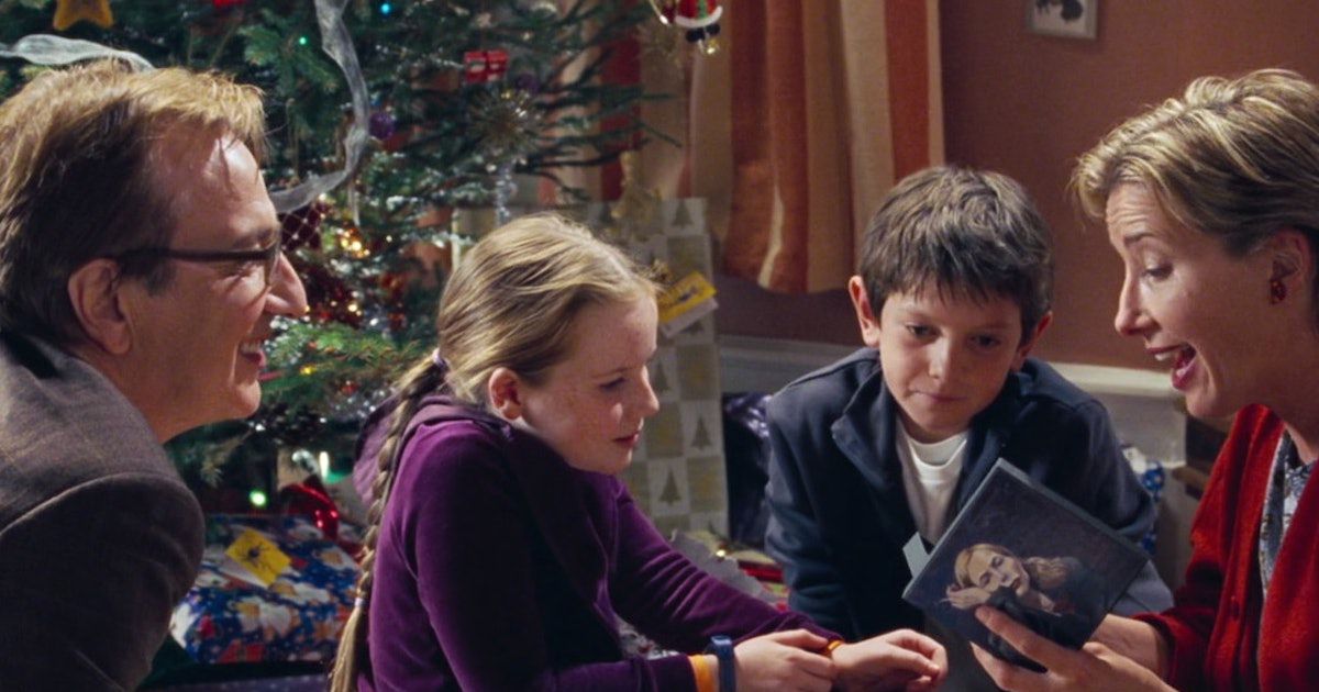 alan rickman guarda mentre emma thompson apre un cd, i loro figli guardano.  c'è un albero di Natale sullo sfondo