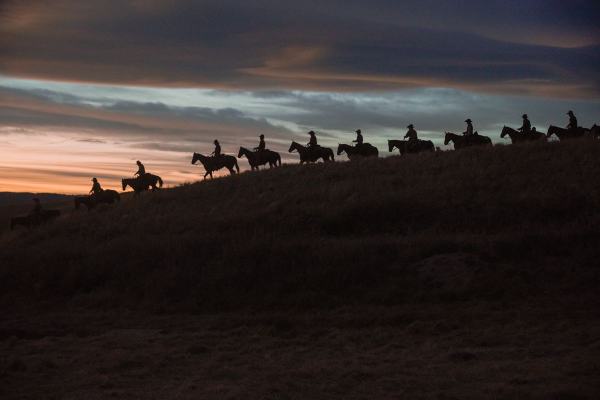 Una fila di cowboy cavalca i propri cavalli lungo un crinale contro il tramonto in una bellissima ripresa dal prequel di Yellowstone 1923.