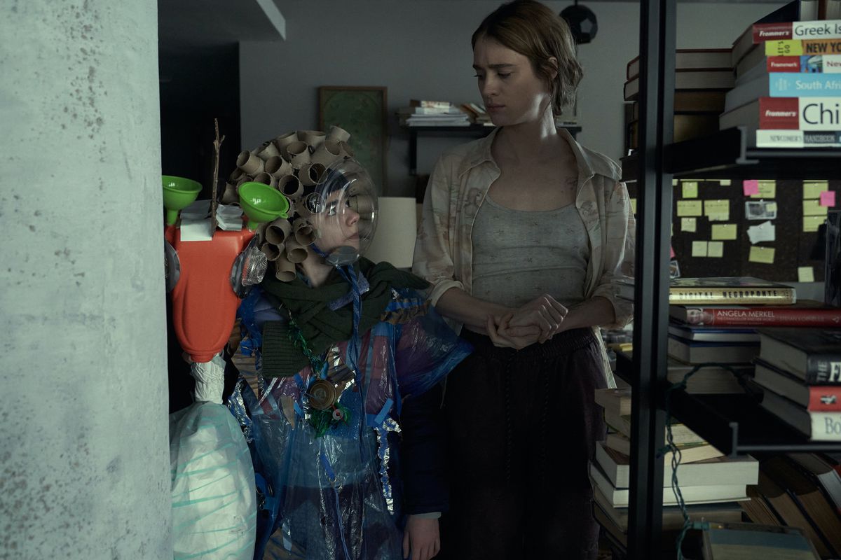 La vecchia Kirsten (Mackenzie Davis) guarda la giovane Kirsten (Matilda Lawler) in un appartamento affollato 