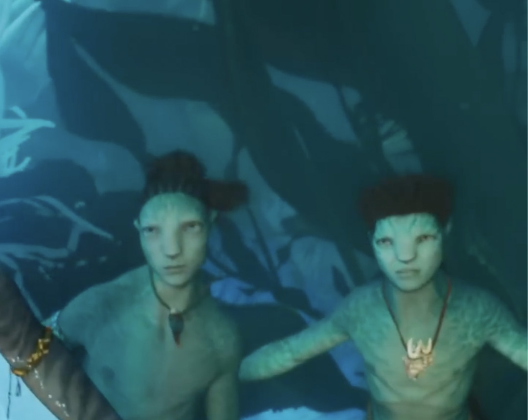due ragazzi na'vi dalla pelle turchese in avatar: la via dell'acqua;  uno ha una crocchia superiore ed è più largo, l'altro è più magro.  entrambi sono sott'acqua