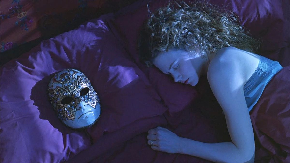 Una donna (Nicole Kidman) dorme nel letto accanto a una maschera ingioiellata posta sul cuscino accanto a lei.