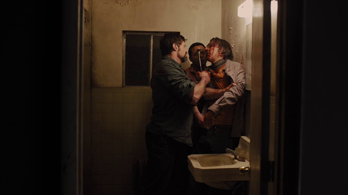 Due uomini (Hugh Jackman, Jake Gyllenhaal) tengono un uomo insanguinato (Paul Dano) contro il muro di un bagno dalle pareti spoglie e lo minacciano con un martello.