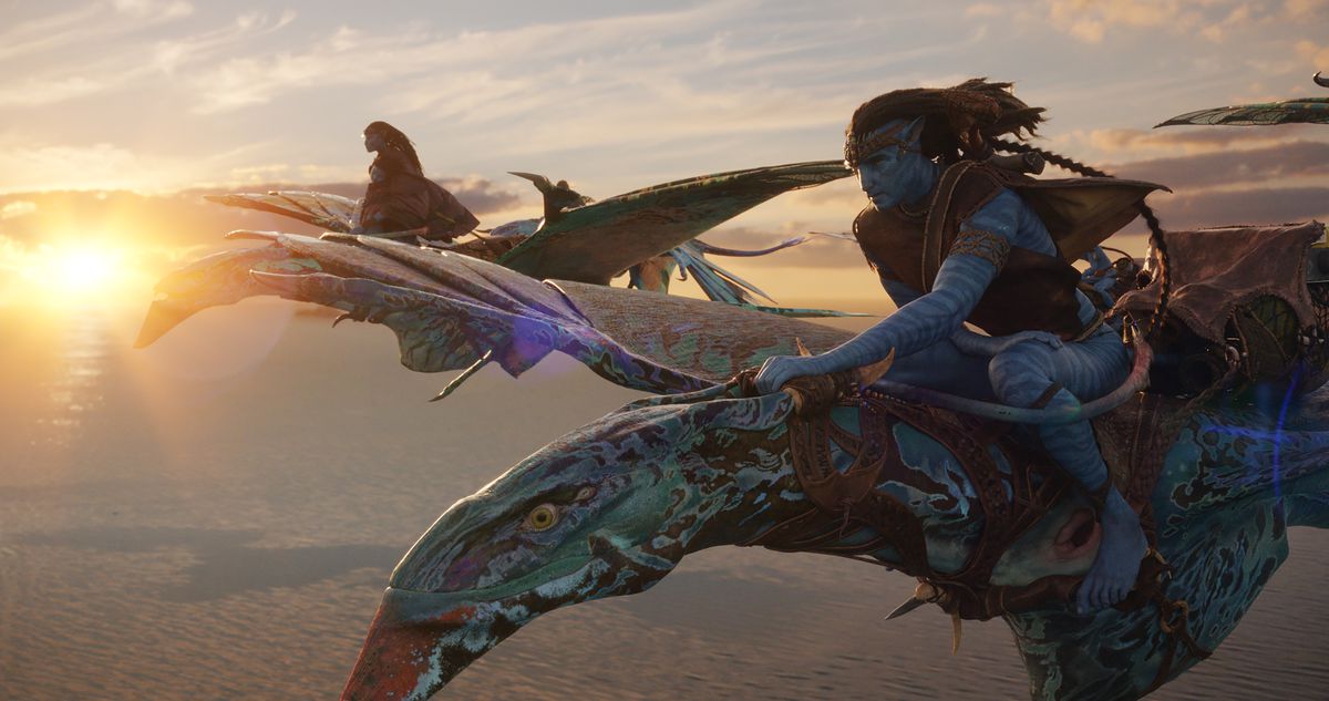 I compagni Na'vi Neytiri (Zoe Saldaña) e Jake (Sam Worthington) volano sulle loro cavalcature blu screziate sopra le nuvole con un tramonto dietro di loro in Avatar: The Way of Water