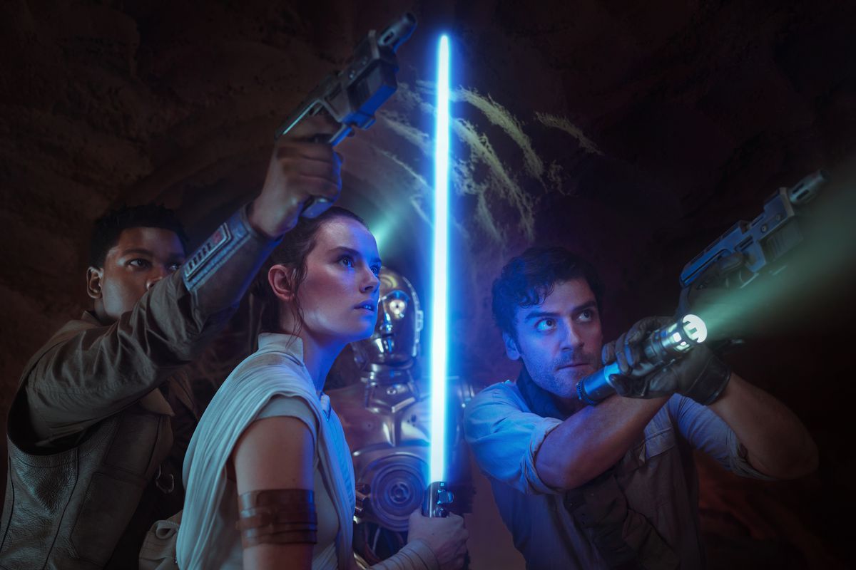 Finn punta la sua pistola verso l'alto, Rey tiene la sua spada laser blu verso l'alto e Poe punta una pistola e una torcia verso l'alto, con C-3PO in piedi dietro di loro, in Star Wars: The Rise of Skywalker