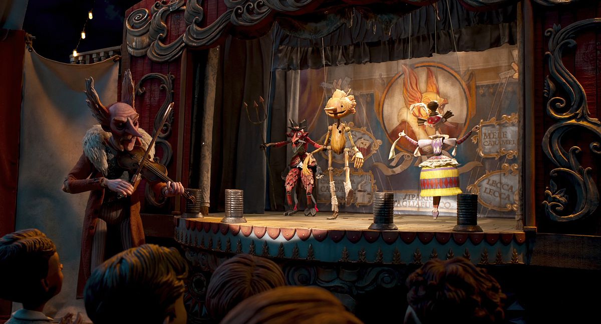 Pinocchio balla sul palco con altri burattini mentre il conte Volpe suona il violino