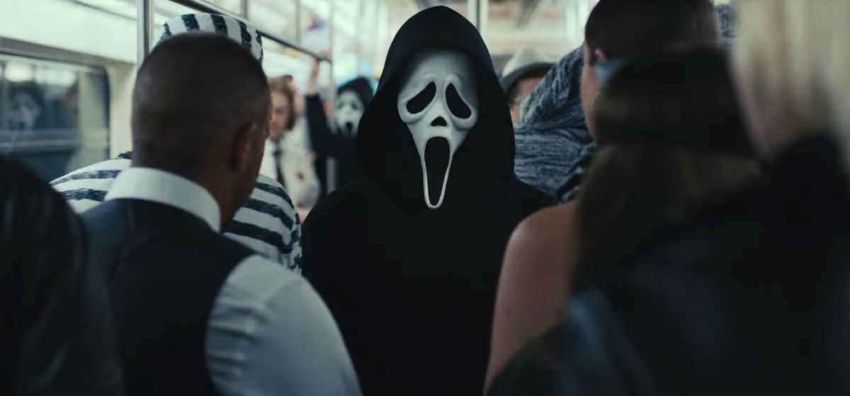 Una persona che indossa una maschera Ghostface si trova su un affollato vagone della metropolitana di New York City in un fotogramma di Scream VI.