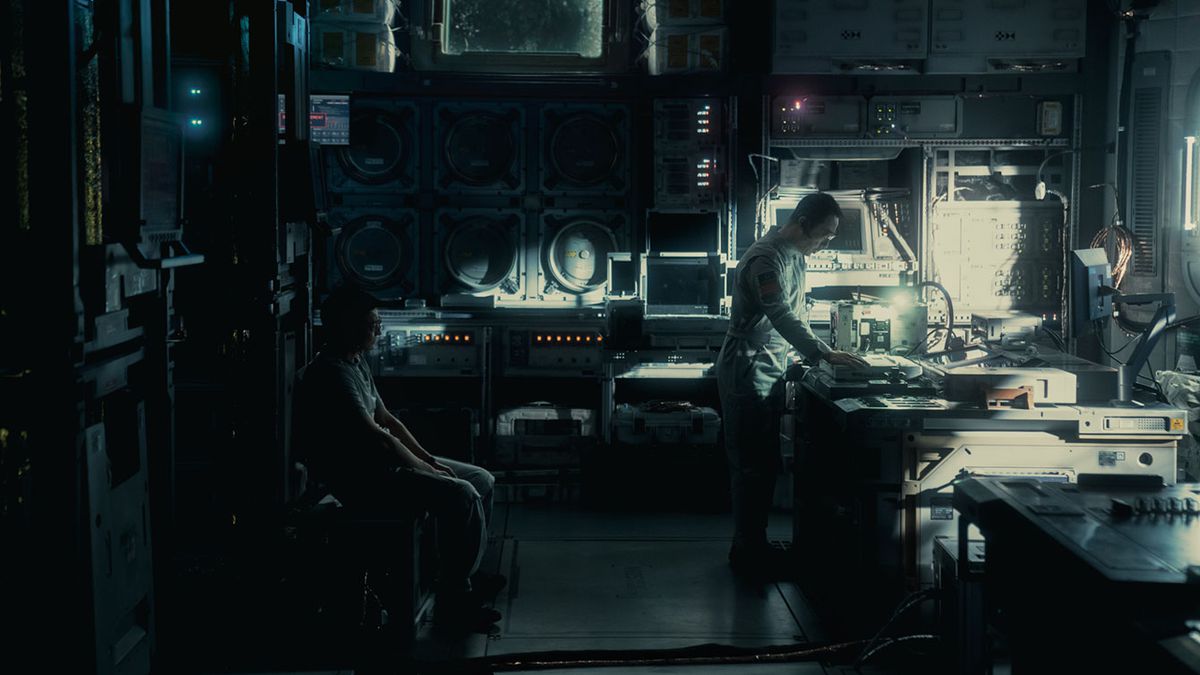 Un uomo si china su un tavolo per guardare qualcosa in un oscuro laboratorio di scienze dall'aspetto futuristico in The Wandering Earth II