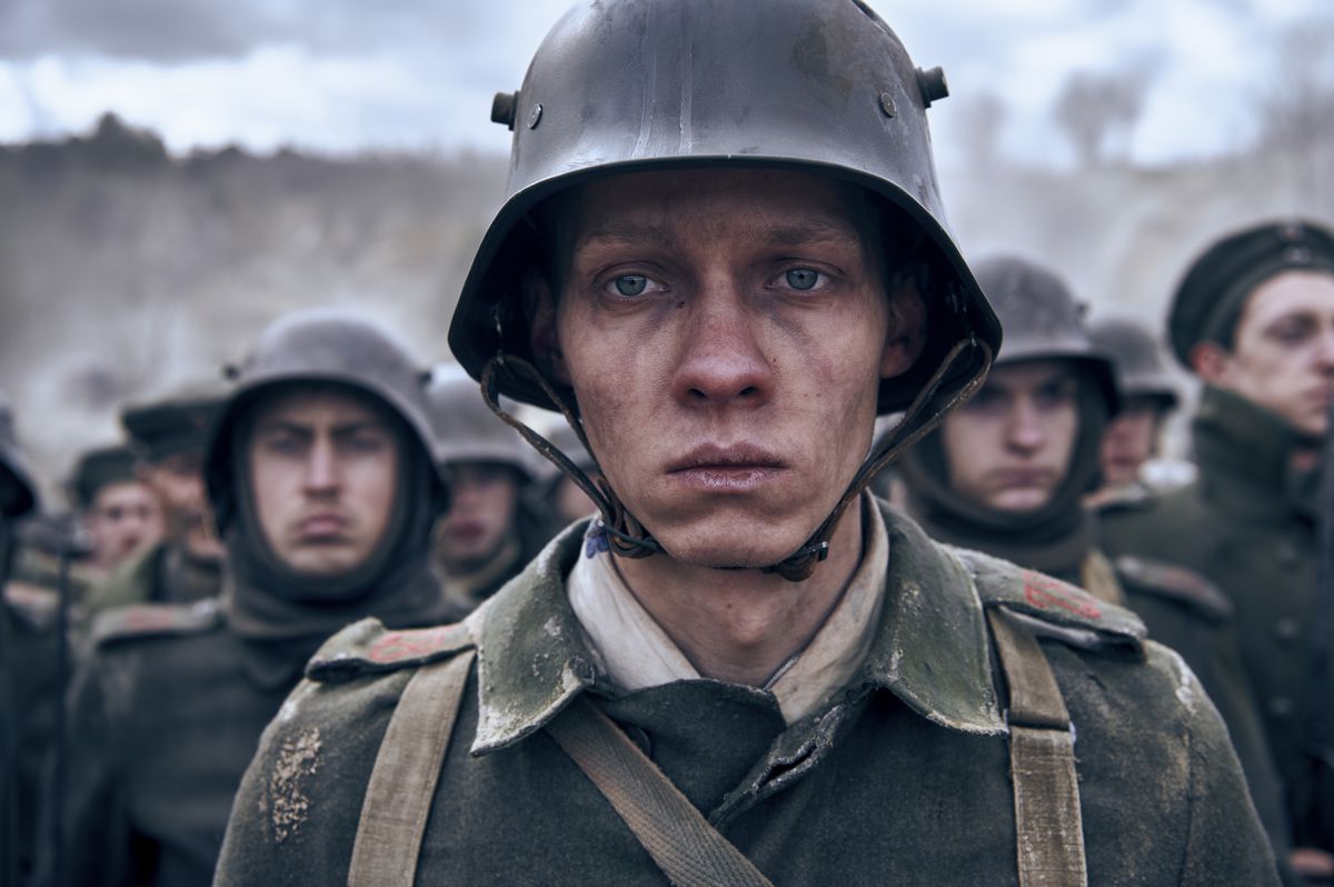 Un giovane uomo in abiti militari della prima guerra mondiale, con un'espressione di devastazione e stanchezza sul viso.