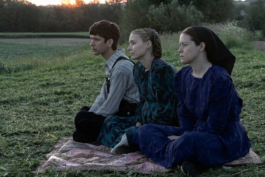 Ben Whishaw, Rooney Mara e Jessie Buckley si siedono su una coperta nell'erba in Donne che parlano.