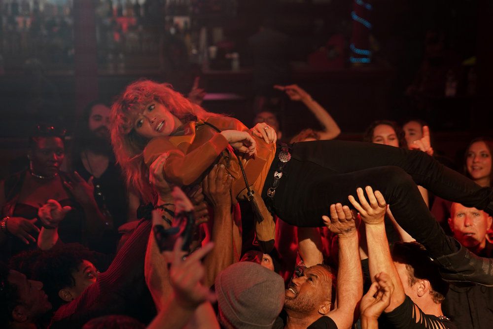 Charlie (Natasha Lyonne) viene trasportato da una folla delirante di metallari in Poker Face