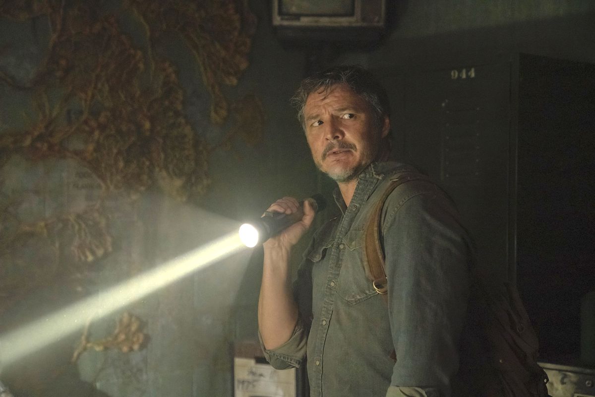 Pedro Pascal nei panni di Joel tiene in mano una torcia elettrica in una stanza buia e ammuffita nello show della HBO The Last of Us