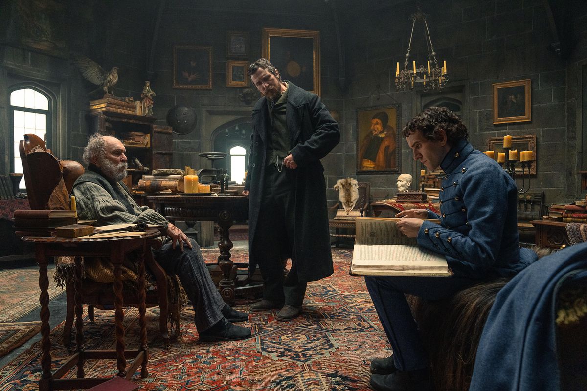 Due uomini siedono in una sala studio (Robert Duvall, Harry Melling) mentre un uomo è in piedi con la mano appoggiata su un tavolo (Christian Bale).