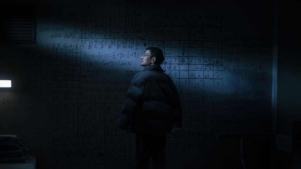 Un uomo si trova in una stanza buia e dall'aria gelida di fronte a un'immensa lavagna ricoperta di simboli e formule matematiche, debolmente illuminata da un unico raggio di luce, in The Wandering Earth II