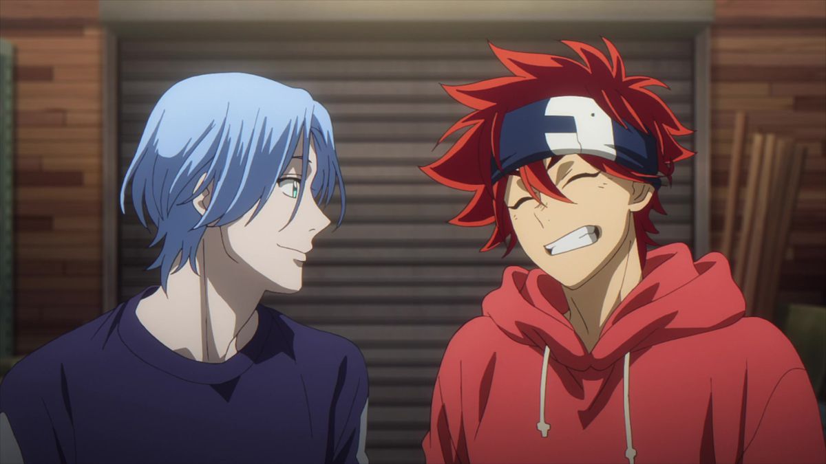 Un ragazzo anime dai capelli blu si trova accanto a un ragazzo anime sorridente dai capelli rossi.