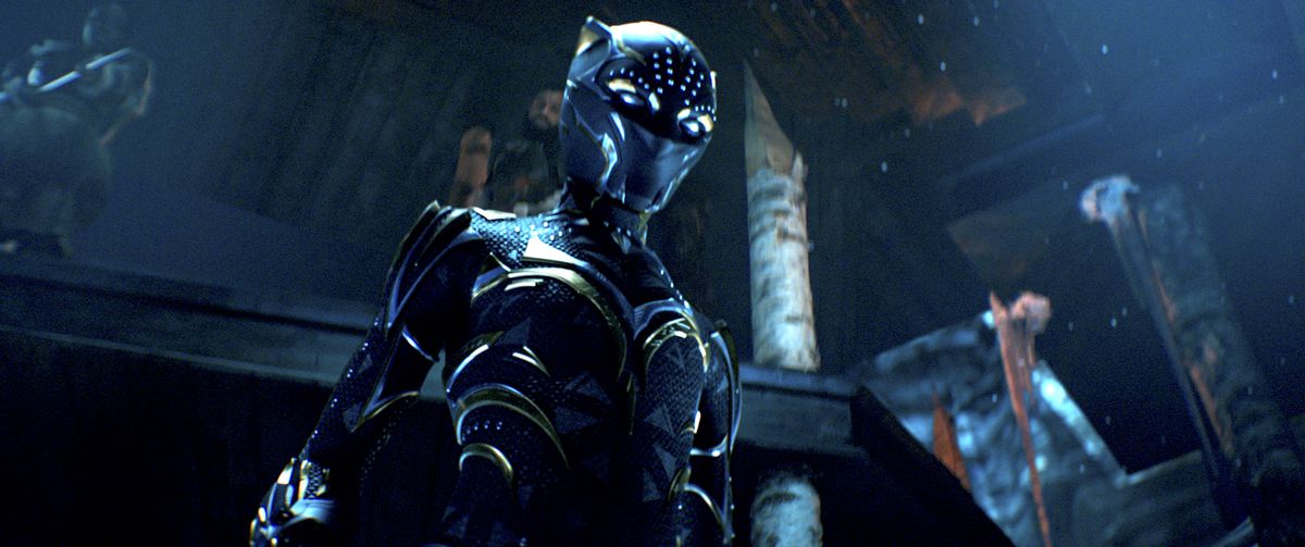 Shuri nel suo abito Black Panther striato d'oro, in piedi in una buia sala del trono, in Black Panther: Wakanda Forever