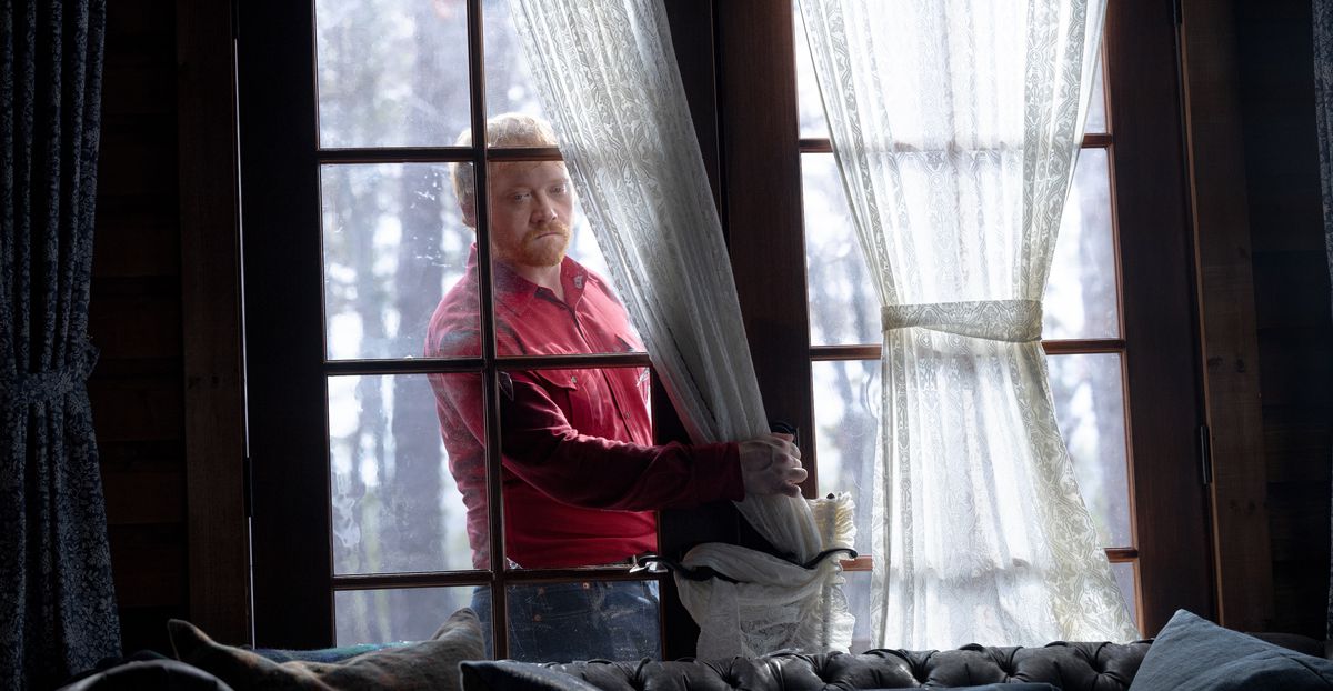 Redmond (Rupert Grint), un uomo magro dai capelli rossi con una maglietta rosso vivo, sfonda il vetro di una serie di porte del patio mentre forza l'ingresso nella cabina in Bussa alla cabina