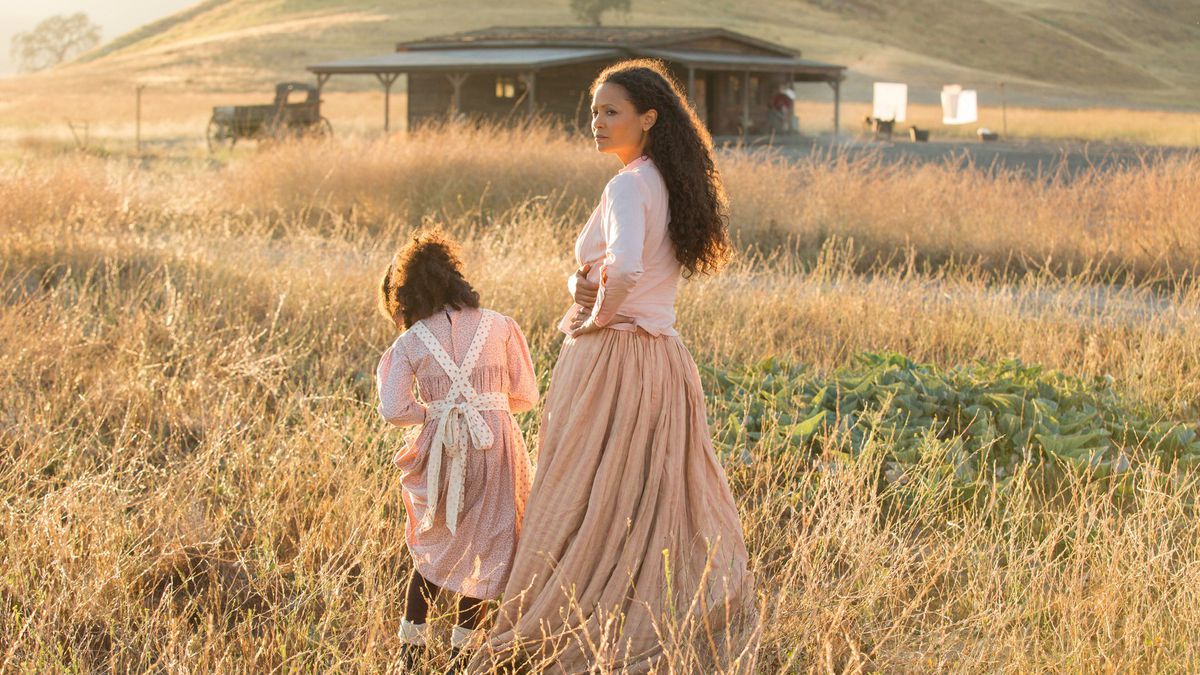 Maeve (Thwandie Newton) e sua figlia camminano attraverso un campo di paglia verso una capanna nella stagione 2 di Westworld