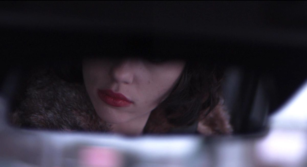 Uno specchietto retrovisore mostra la metà inferiore del volto di Scarlett Johansson in Under the Skin