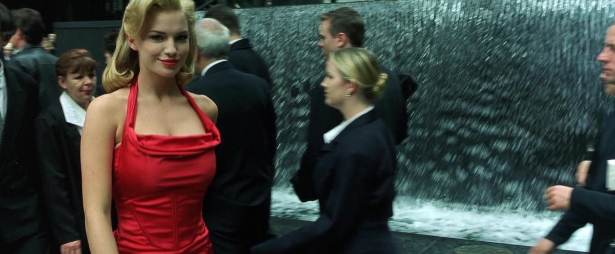 Fiona Johnson sorride mentre guarda nella telecamera e indossa un vestito rosso in The Matrix