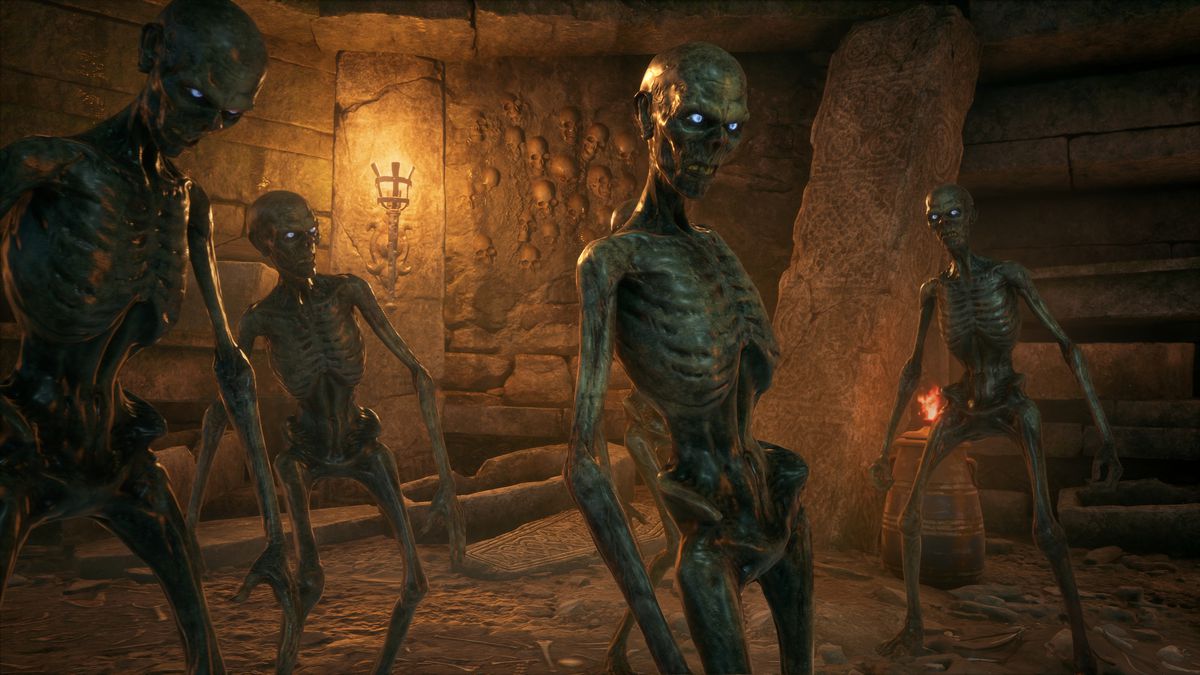 un gruppo di inferi, scheletri con occhi ardenti, cammina a destra della telecamera in un dungeon in Hogwarts Legacy