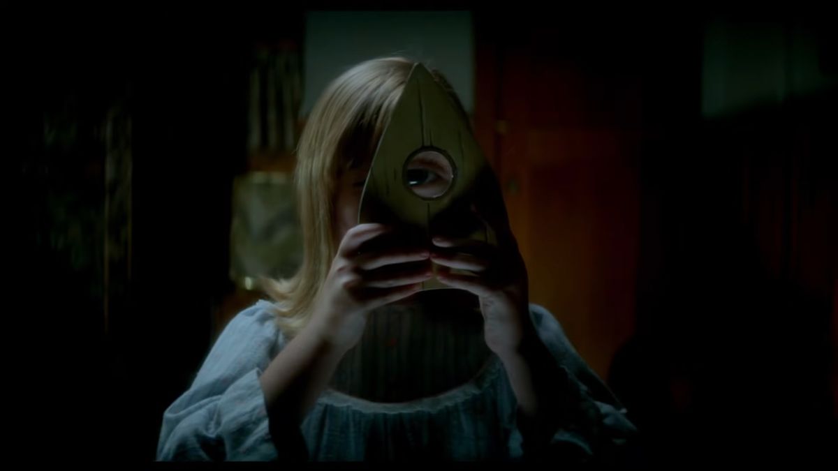Una giovane ragazza guarda attraverso una planchette ouija in Ouija: Origin of Evil