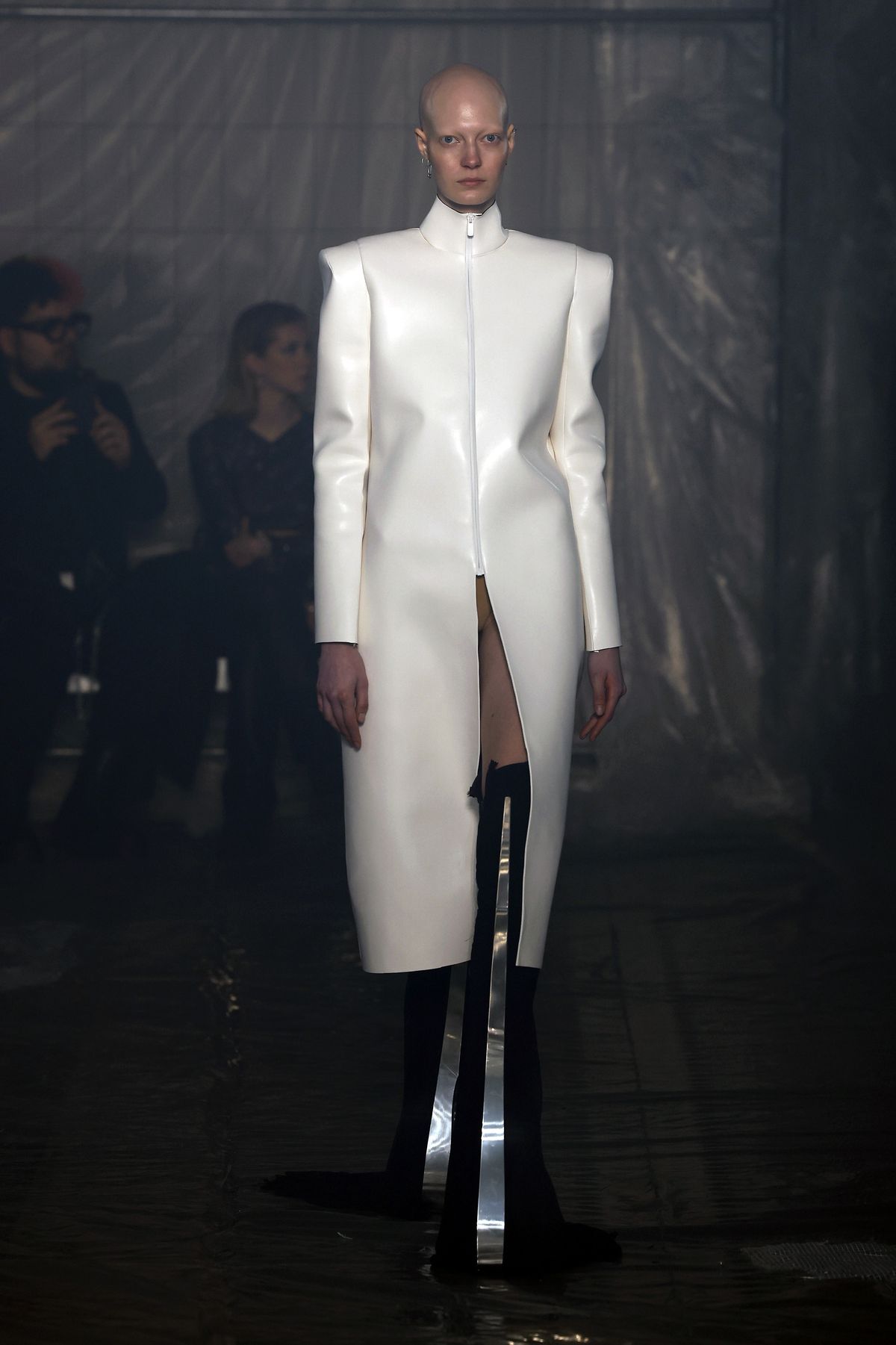 Una modella che indossa un lungo cappotto di pelle bianca e tacchi con sporgenze a forma di spada cammina sulla passerella della sfilata di Han Kjobenhavn alla settimana della moda di Milano.