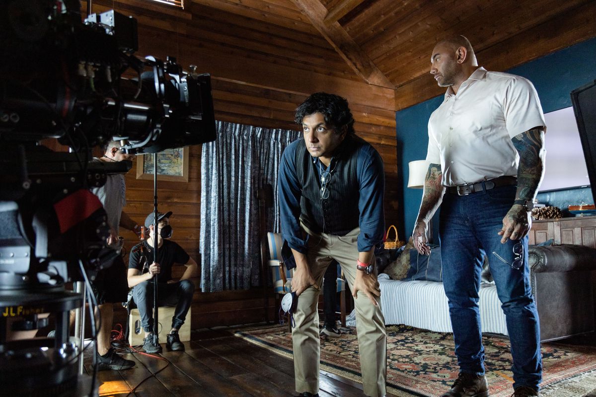 M. Night Shyamalan si accovaccia davanti alla telecamera sul set di Knock at the Cabin con la star Dave Bautista.