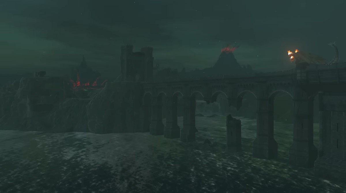 Un'immagine da un trailer di The Legend of Zelda.  Mostra un gigantesco ponte di pietra che attraversa l'acqua.  È davvero molto buio fuori e c'è un vulcano in lontananza.  Sulla destra del ponte puoi vedere un mostro che lo attraversa.  Ha tre teste e fuoco che esce dalla sua testa. 