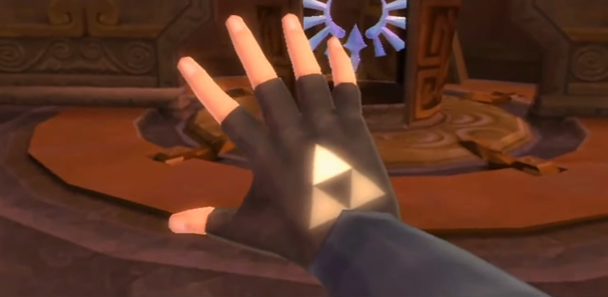 Un primo piano della mano di Link in The Legend of Zelda: Skyward Sword.  I tre triangoli che compongono la Triforza brillano attraverso il suo guanto, con il triangolo superiore che brilla di più.