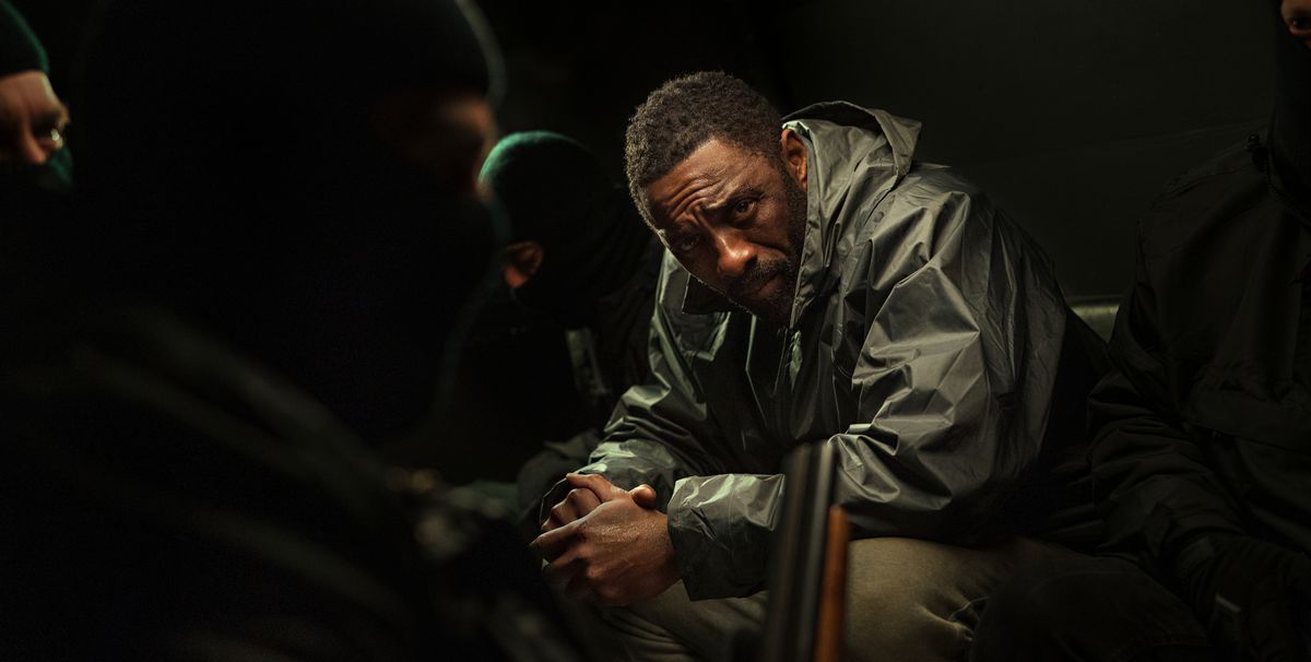 John Luther (Idris Elba) siede in una stanza molto buia con le mani giunte davanti a sé e fissa la telecamera, circondato da tre uomini con passamontagna che coprono il viso, in Luther: The Fallen Sun
