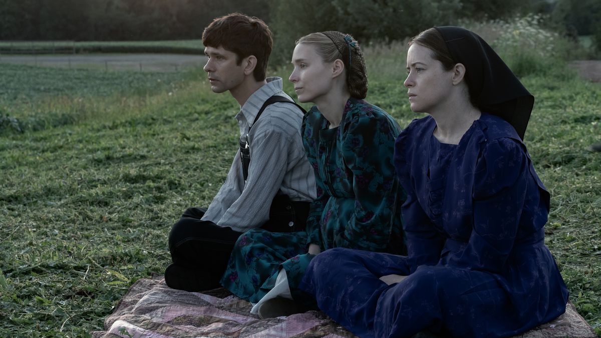 Un uomo (Ben Whishaw), una donna (Rooney Mara) e un'altra donna (Claire Foy) siedono su una coperta che si affaccia su un campo di erba verde.