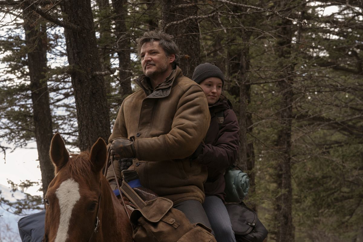 Joel (Pedro Pascal) sorride su un cavallo con Ellie (Bella Ramsey) che cavalca dietro di lui guardando in basso