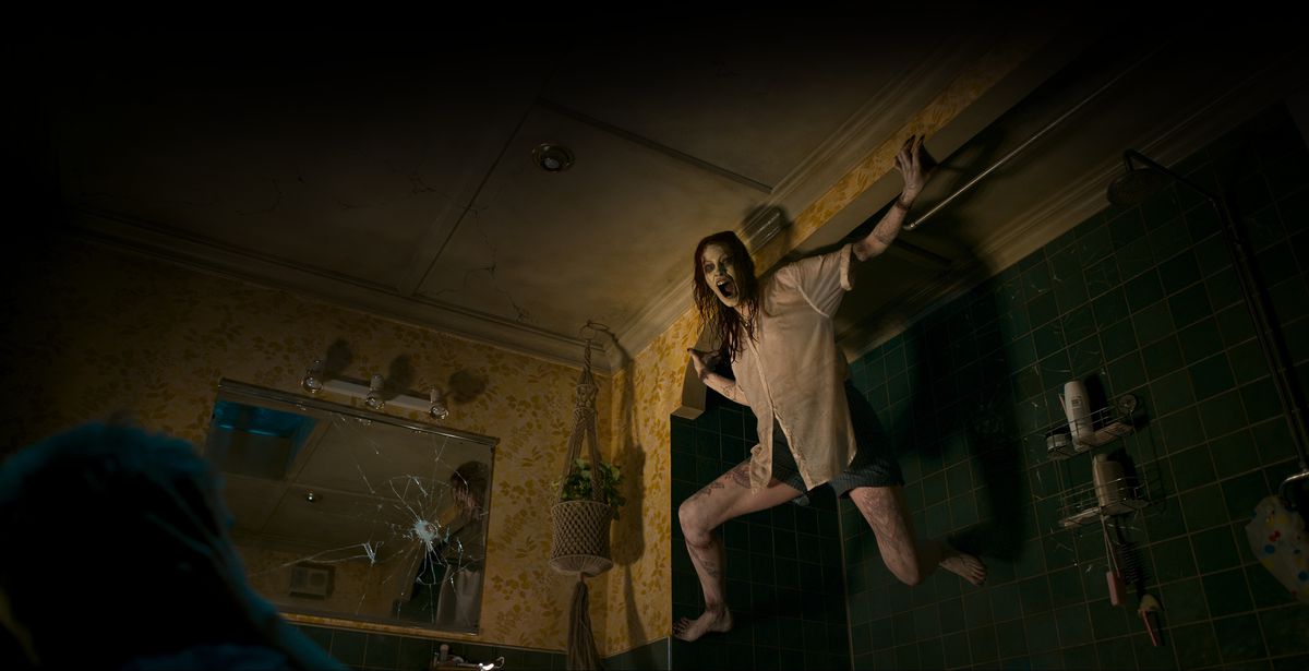 Deadite Ellie (Alyssa Sutherland), appena posseduta, sibila attraverso la bocca annerita mentre si aggrappa a un muro nel suo appartamento buio in Evil Dead Rise