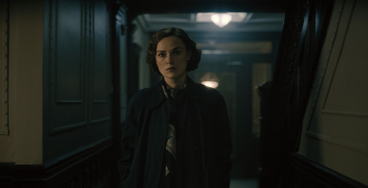 Una donna (Keira Knightley) con un cappotto blu scuro si trova in un corridoio poco illuminato