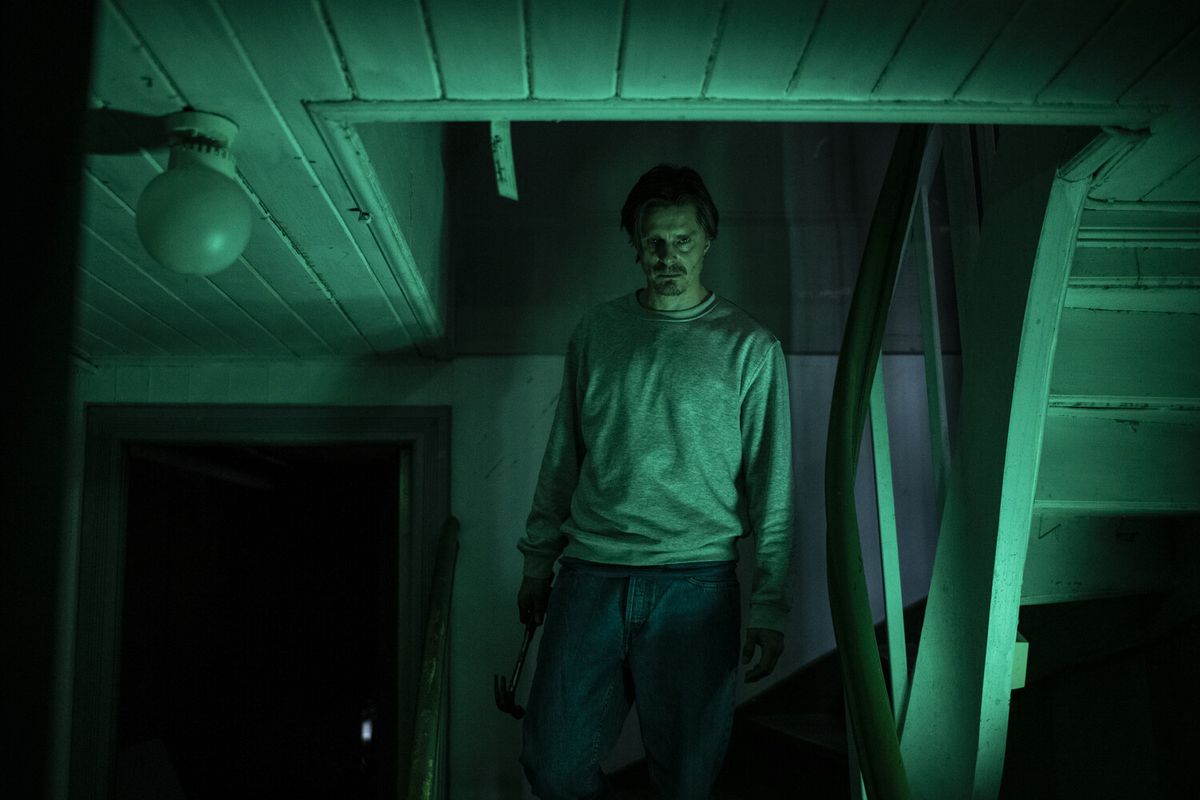 Un uomo dall'aspetto nordico tiene in mano un martello su una scala illuminata di verde a Leave.