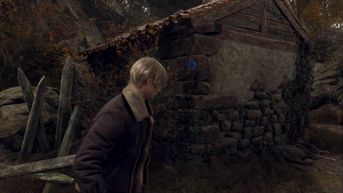 Leon S Kennedy si trova accanto a un medaglione blu nell'area della Fattoria del remake di Resident Evil 4