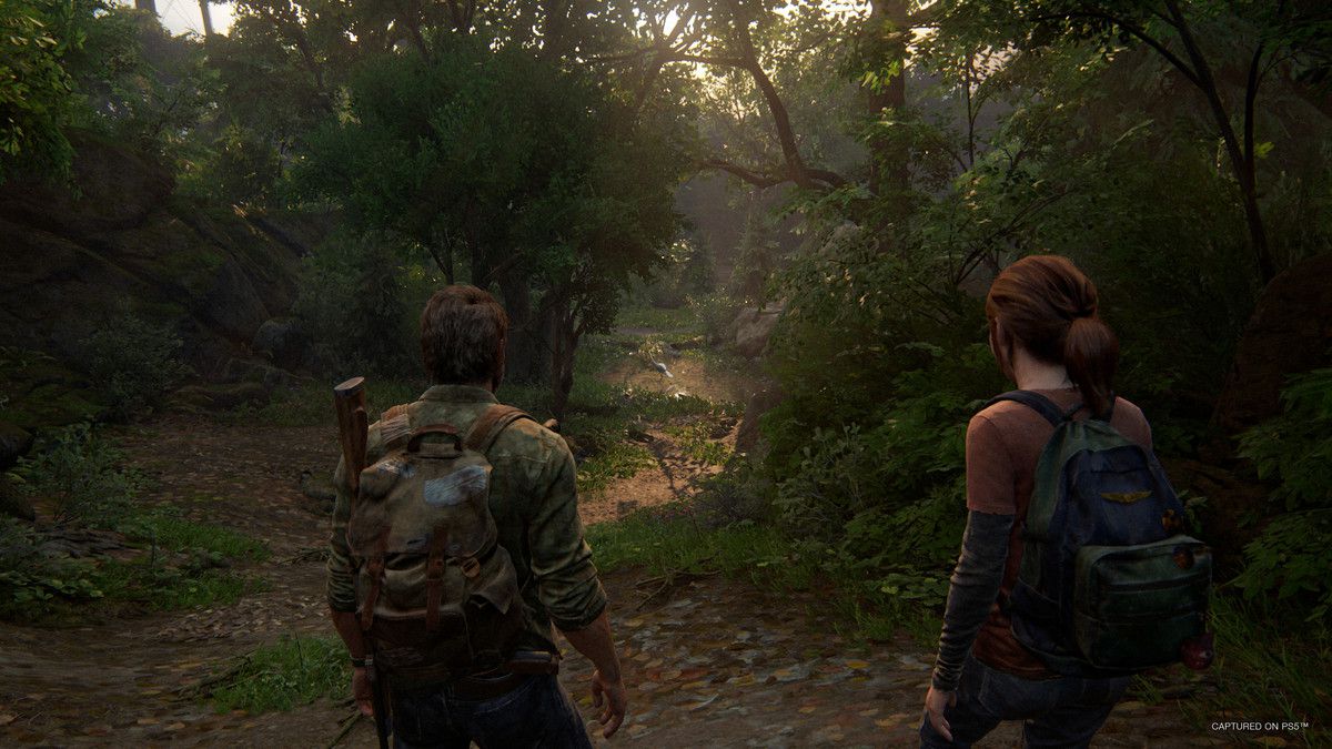 Joel ed Ellie attraversano un'area boscosa in The Last of Us Part I