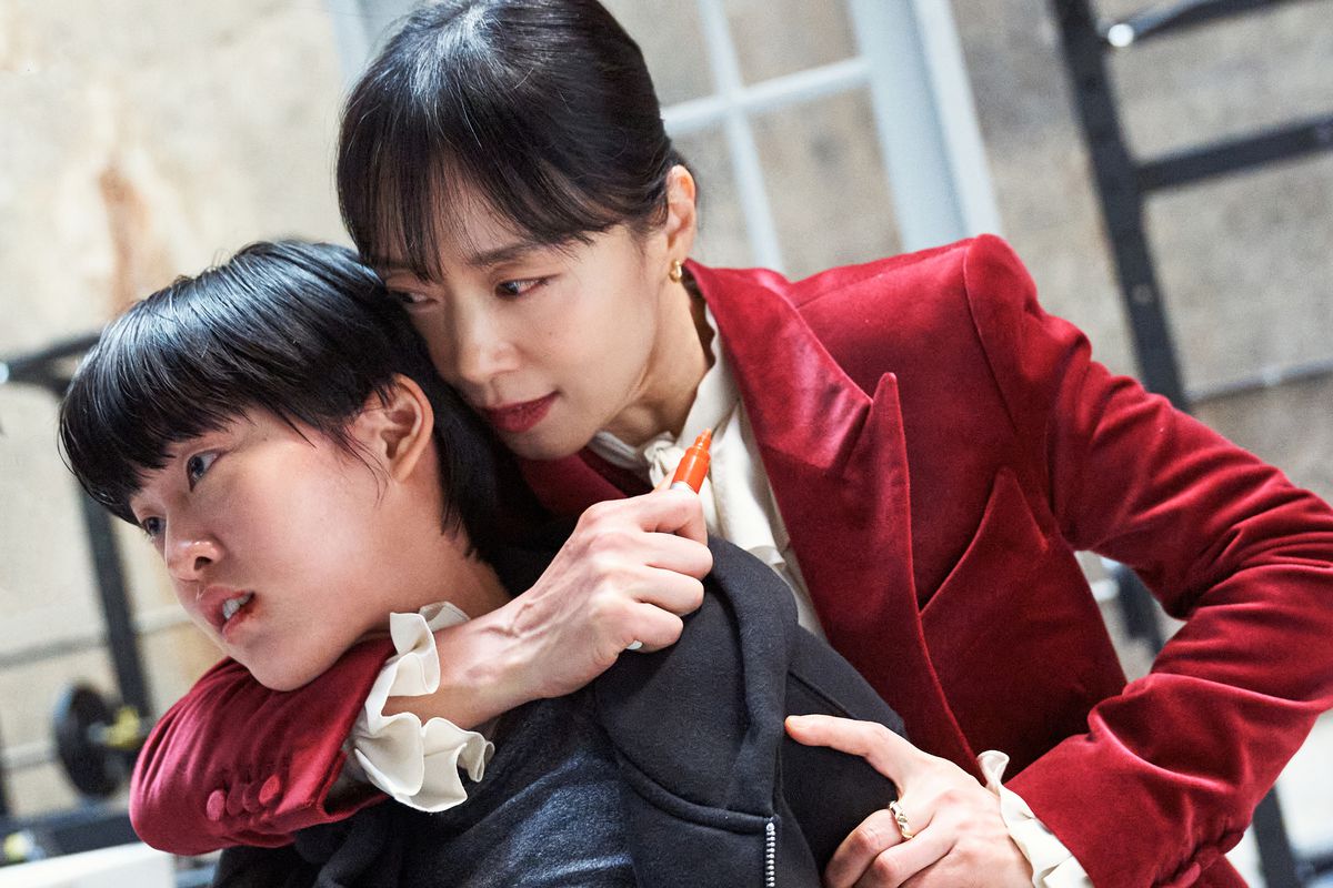 Jeon Do-Yeon, vestito di rosso come Gil Boksoon, tiene Lee Yeon in una presa soffocante mentre tiene in mano un pennarello arancione in Kill Boksoon.