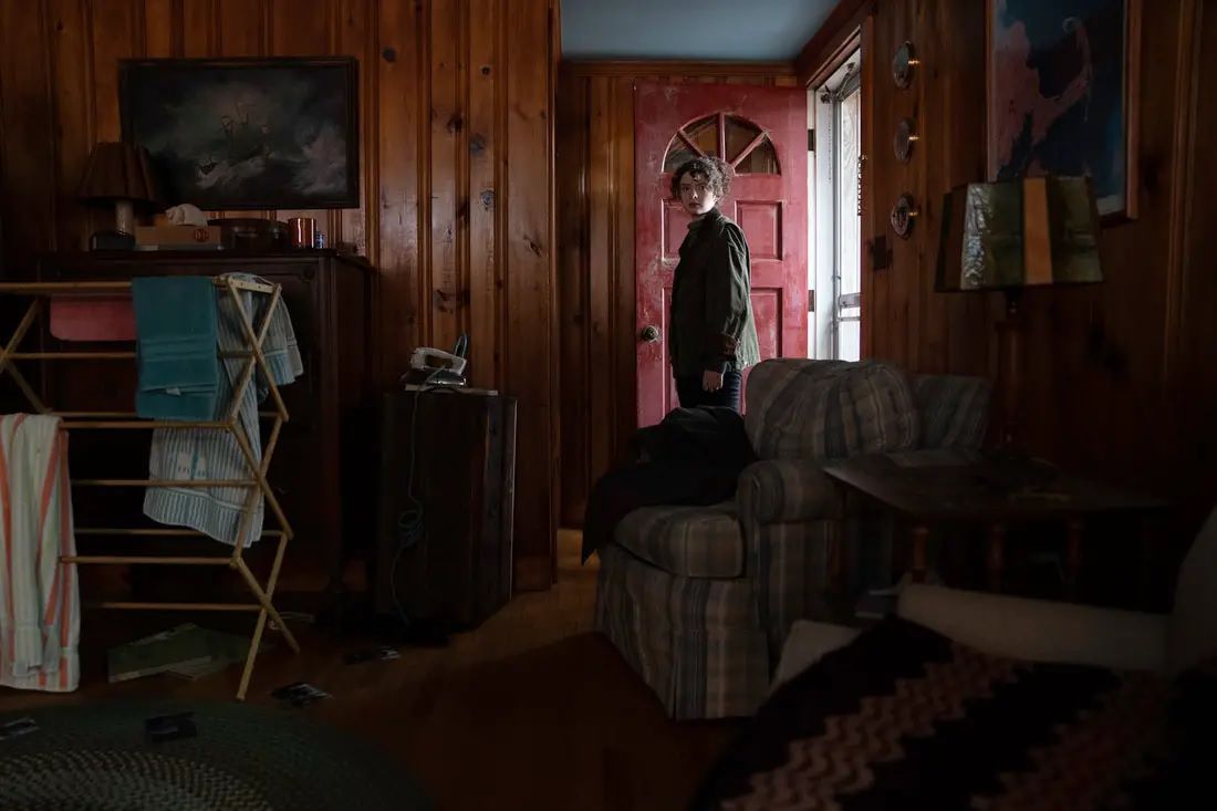 Un giovane entra in una casa disordinata con una porta rossa aperta in The Unheard.