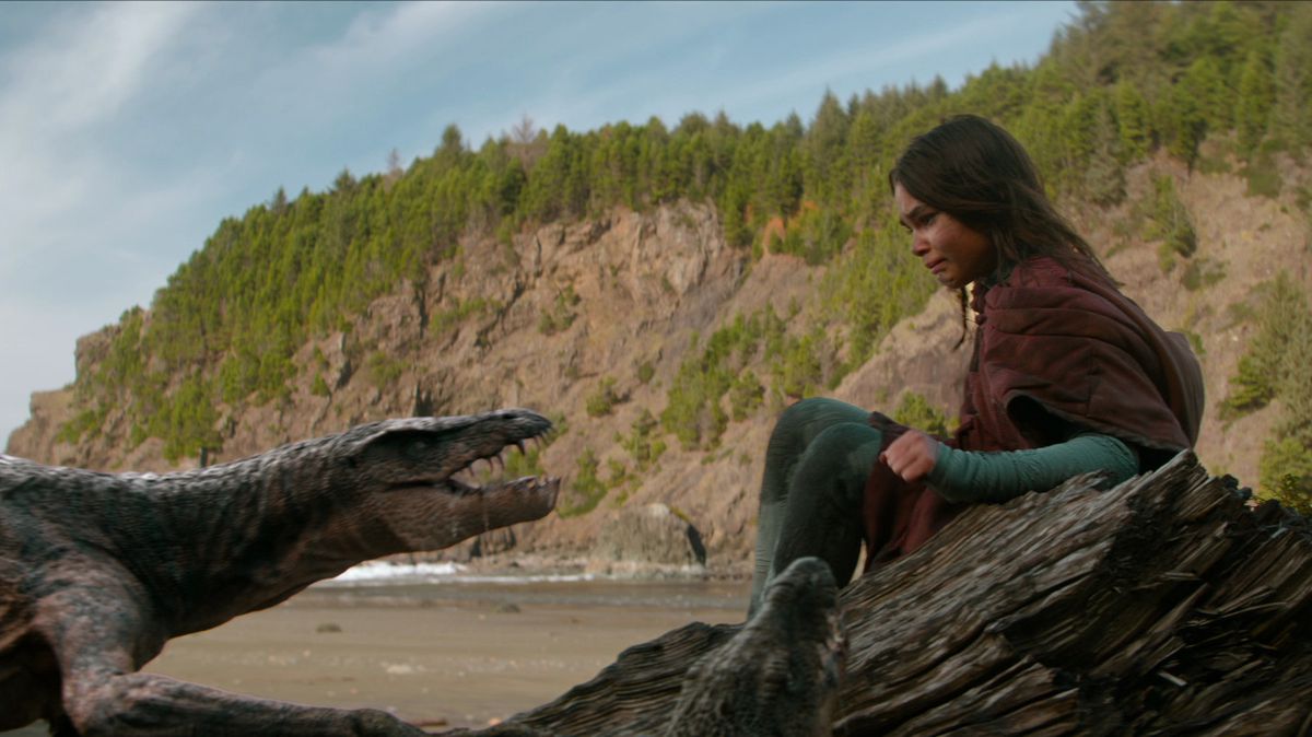Un dinosauro simile a una lucertola sibila all'adolescente brunetta che si indietreggia su una roccia nel film 65