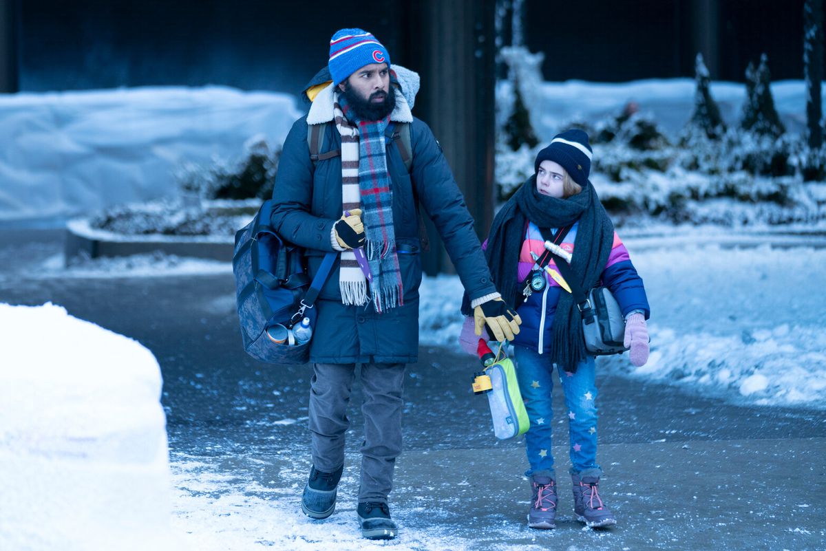 Un uomo (Himesh Patel) e una bambina (Matilda Lawler) camminano attraverso un paesaggio ghiacciato vestiti con abiti invernali.