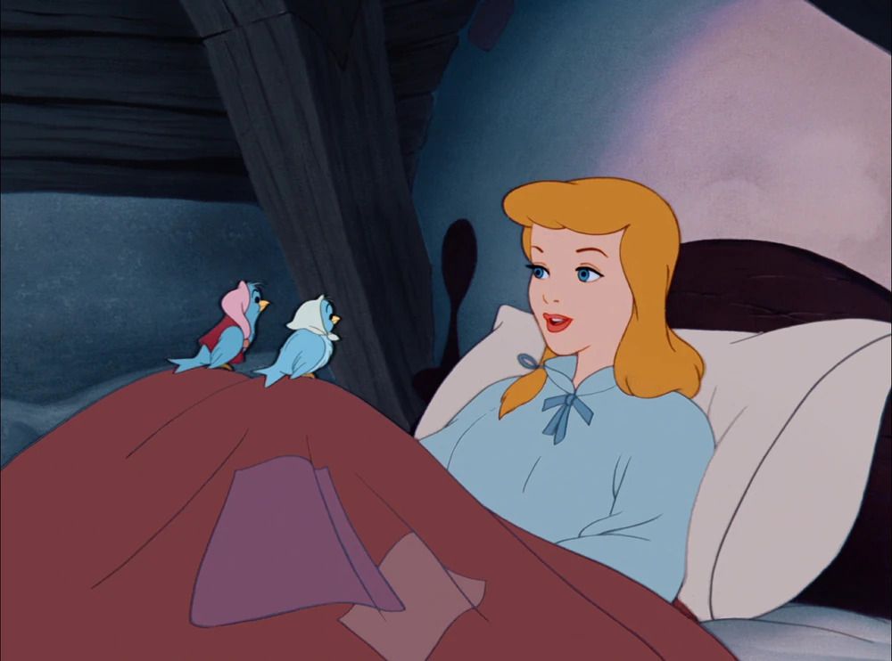cenerentola in camicia da notte blu seduta sul letto e parlando con alcuni amici uccelli