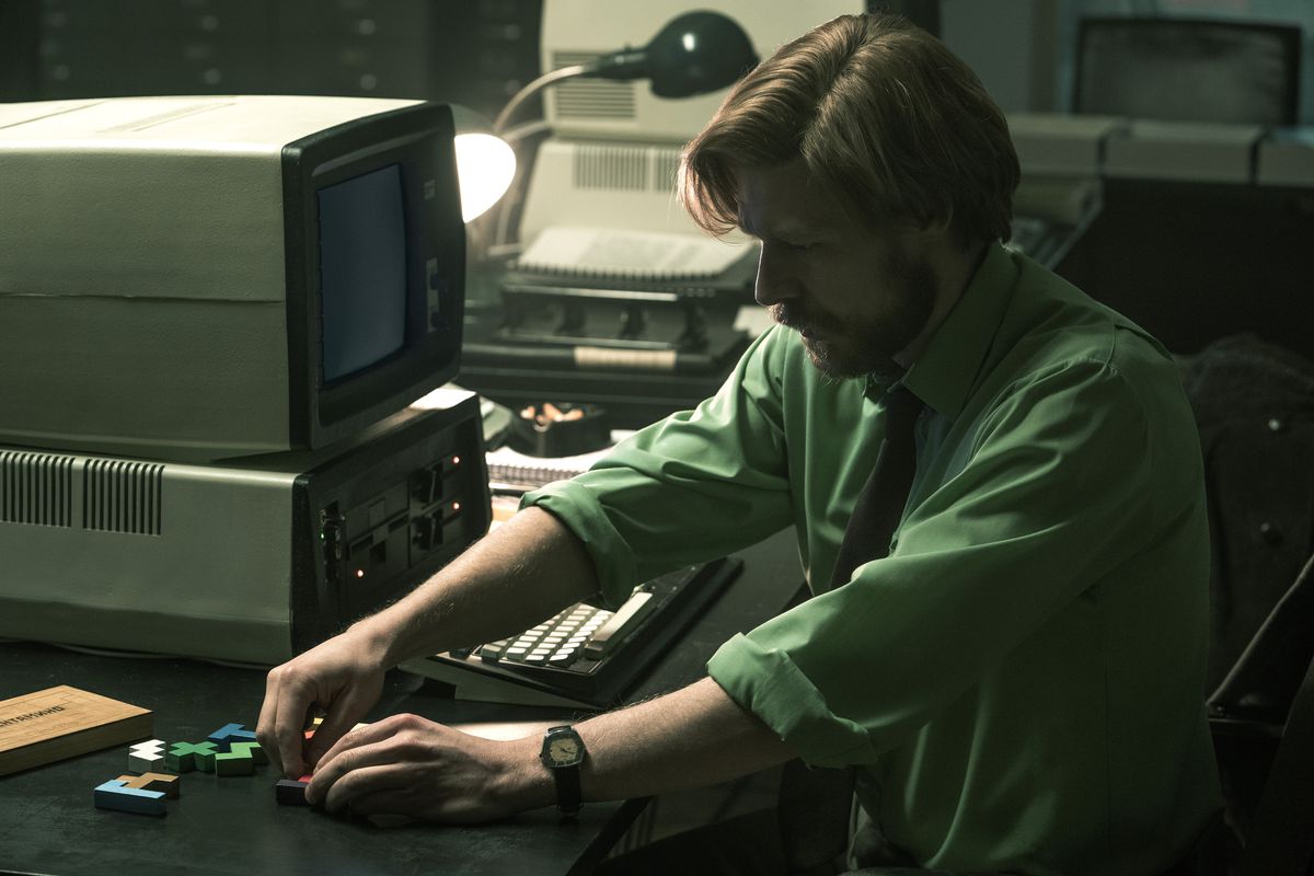 Nikita Efremov, nei panni di Alexey Pajitnov, si interroga sui pezzi dei pentamini sulla sua postazione di lavoro in un fotogramma del film Tetris