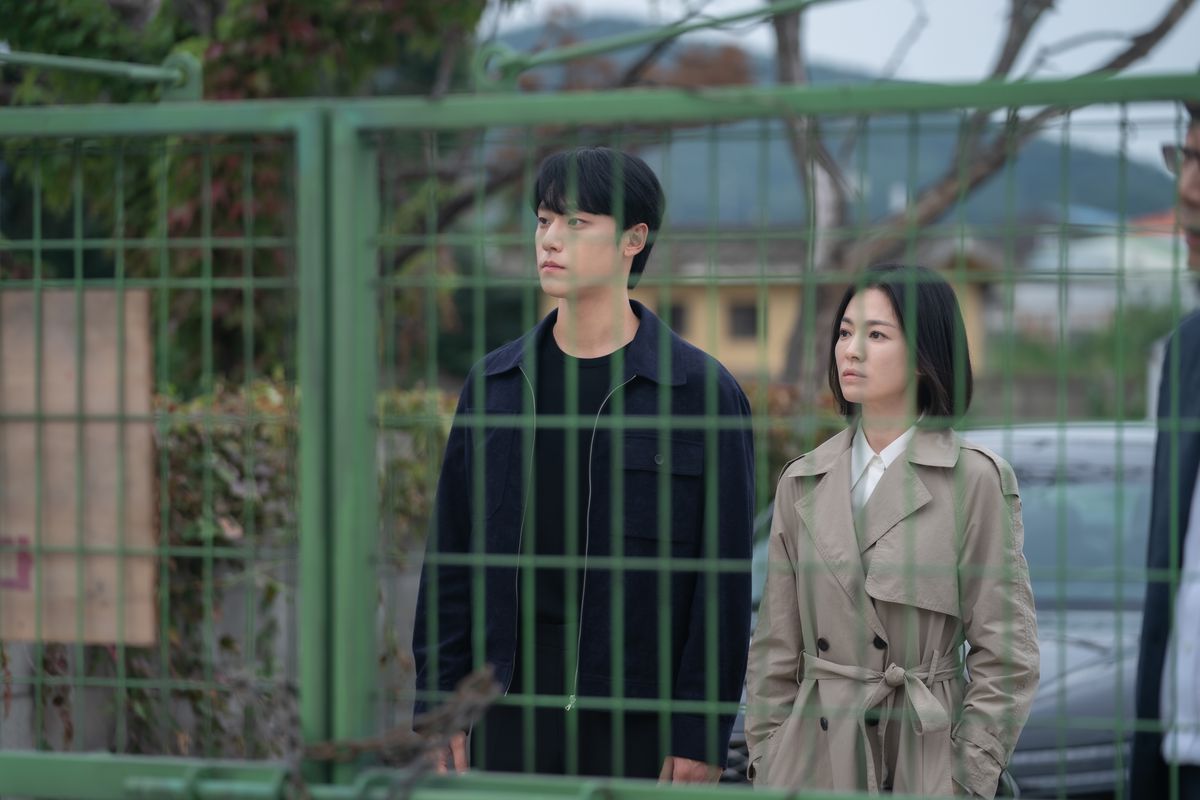 Lee Do-Hyun nei panni di Joo Yeo-jeong e Song Hye-kyo nei panni di Moon Dong-eun in piedi dall'altra parte di una recinzione